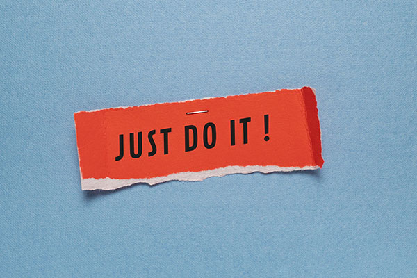 Man sieht ein rotes markantes Post-it mit Aufschrift "Just do it" in Großbuchstaben.